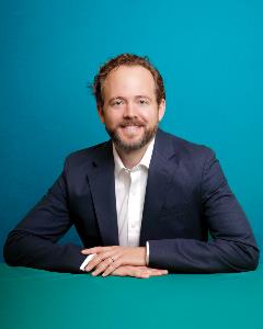 Justin Reed headshot with blue-green background