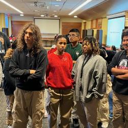 Group of students watch as mentor organizes data on the whiteboards