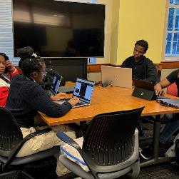 Groups of students work on database activity code academy